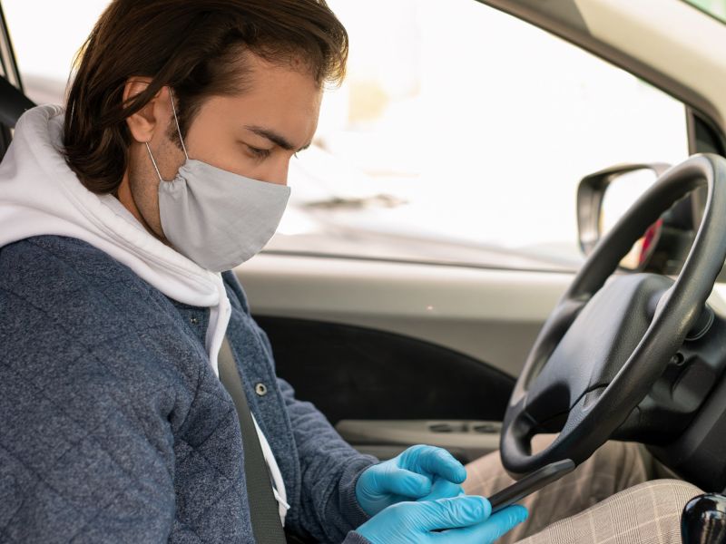 man with mask on in car